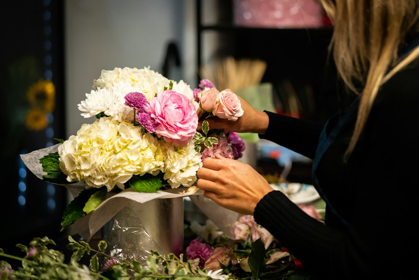 Floristin bindet einen Strauß mit Hortensien und Rosen
